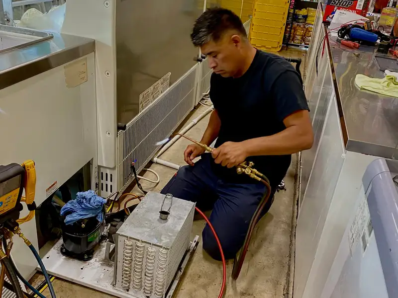 Pacific Breeze HVAC technician brazing a line on commercial refrigeration equipment in a restaurant