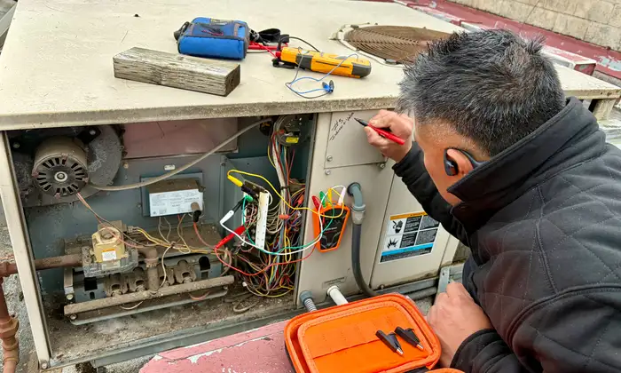 Pacific Breeze HVAC technician troubleshooting the wiring on a commercial rooftop HVAC unit